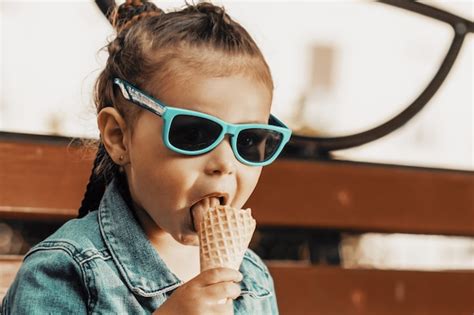 Premium Photo A Girl In A Denim Suit And Sunglasses Eats Ice Cream On