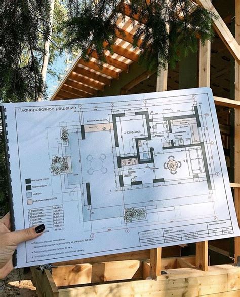 A Person Holding Up A Blueprint For A House