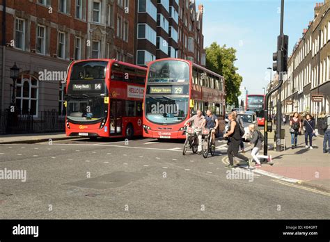 People Riding Transport For London Bikes At A Road Junction Besides Two