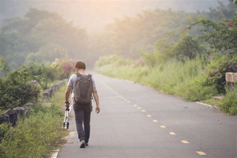 Lonely Man Holding A Camera And A Tripod Walking On The Road Sunsets