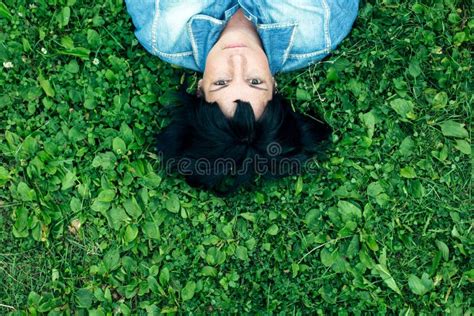 Top View Of A Black Haired Woman Lying On Green Grass Stock Image