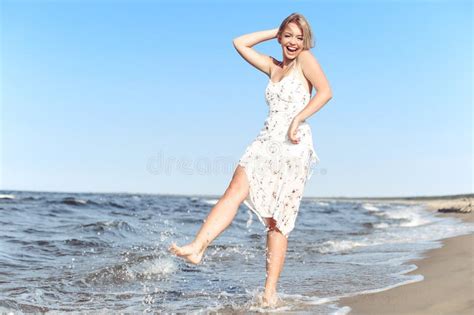 Happy Blonde Beautiful Woman Having Fun On Ocean Beach While Dancing In Waves Stock Photo