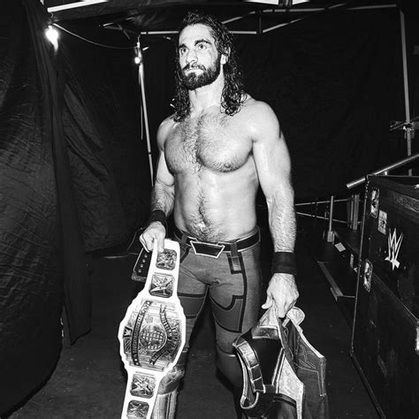 A Man With Long Hair And Beard Holding A Wrestling Belt Standing In A