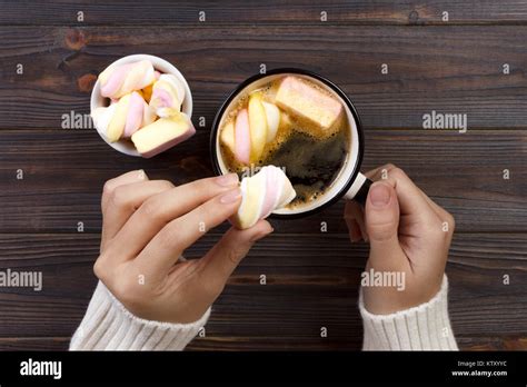 Female Hand Holding Cup Of Hot Cocoa Or Chocolate With Marshmallow On Wooden Table From Above