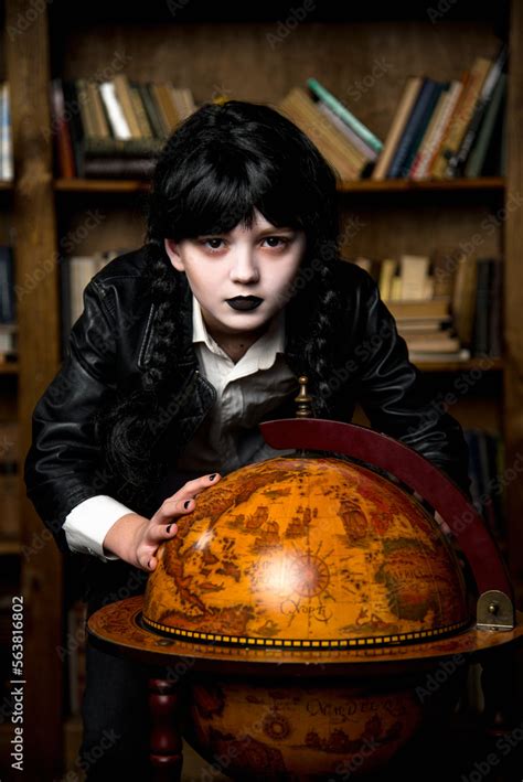 Brunette Gothik Girl Cosplay Wednesday Addams Holding Globe In Her Handa In Dark Library Stock