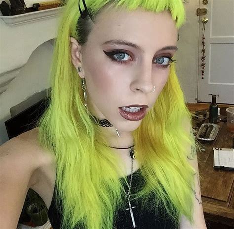 A Woman With Bright Yellow Hair And Piercings On Her Ears Is Posing For