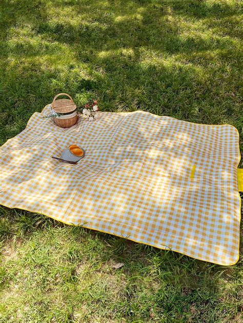 A Yellow And White Checkered Blanket Sitting On Top Of A Grass Covered