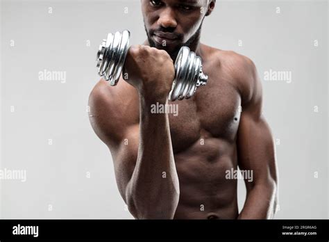 cool young black man lifts a shiny chrome weight. Defined chest and abs ...