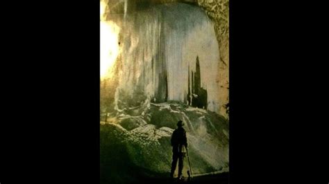 A Man Standing In Front Of A Waterfall With Ice Hanging Off It S Sides