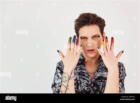 Le jeune homme gay est debout dans le studio et pose pour une caméra Gestuelle et expressions