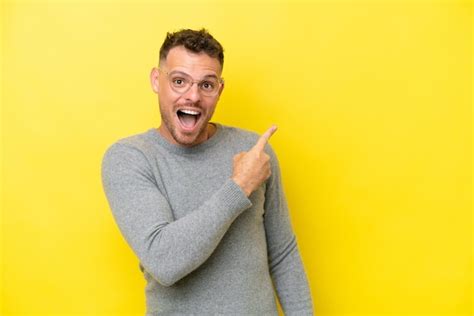 Hombre guapo caucásico joven aislado sobre fondo amarillo sorprendido y