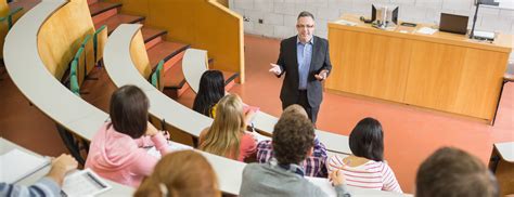 Elegant teacher with students sitting at the college lecture hall - MACC