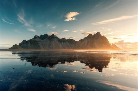 Amanecer sobre la montaña vestrahorn con reflejo en la playa de arena