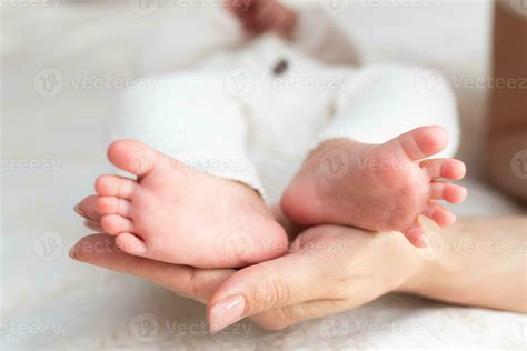 Mother Hugs Legs Of Newborn Baby With Hands Stock Photo At