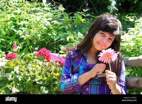 Pretty Eight Year Old Girl Sitting In The Garden Holding A Pink Flower