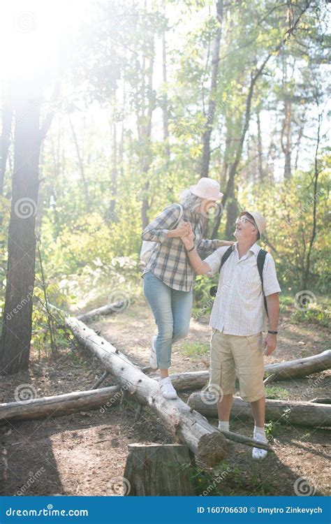 Loving Husband Supporting His Wife Standing On The Tree Roots Stock