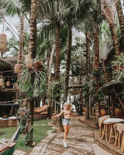 A Woman Walking Down A Path Between Palm Trees