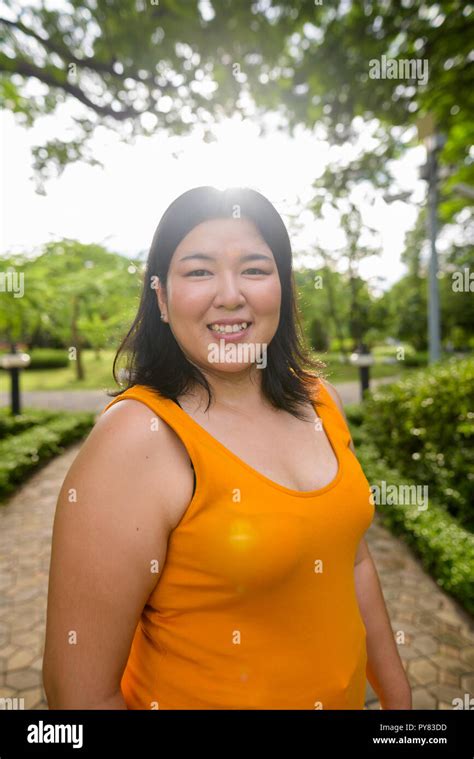 Beautiful Overweight Asian Woman Smiling In Park With Lens Flare Stock