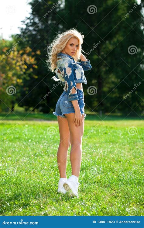 Beautiful Blonde Woman Dressed In A Denim Jacket And Shorts Stock Image