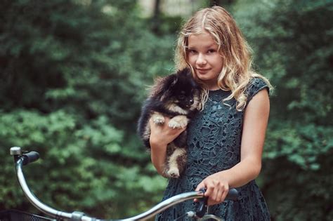 Portrait D une Petite Fille Blonde Vêtue D une Tenue Décontractée Tient Un Joli Chien Spitz