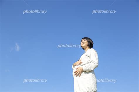 青空を背景に大きなお腹に希望を持って手を当てている臨月の妊婦の様子 妊娠 臨月 愛 楽しみ 幸せイメージ 写真素材 5804534 フォトライブラリー Photolibrary