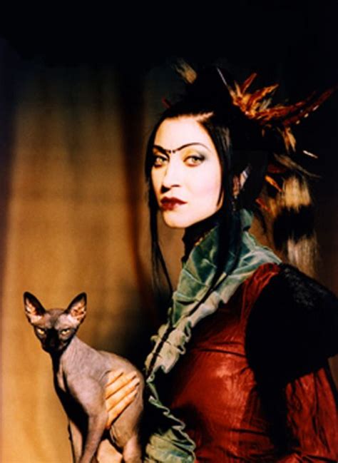 A Woman Holding A Cat In Her Right Hand And Looking At The Camera With