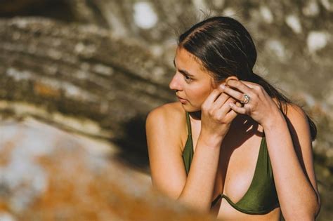 Junge Frau in einem grünen Bikini genießt Sonne am Strand während sie für Kamera