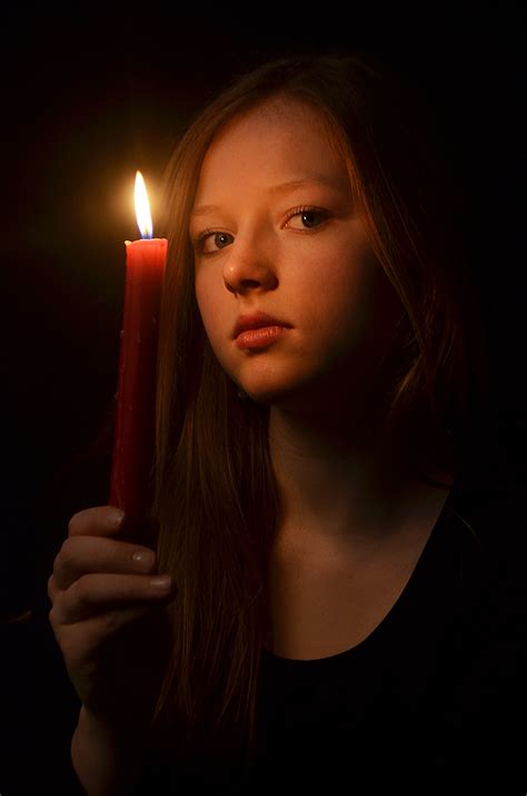 A Woman Holding A Lit Candle In Her Hand