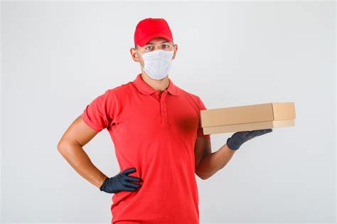 Delivery Man Holding Cardboard Box With Hand On Waist In Red Uniform