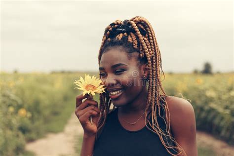 African American Girl In A Field Of Yellow Flowers At Sunset Stock