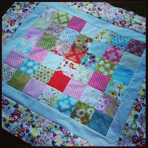 A Colorful Patchwork Quilt Is Laying On Top Of A Tablecloth That Has