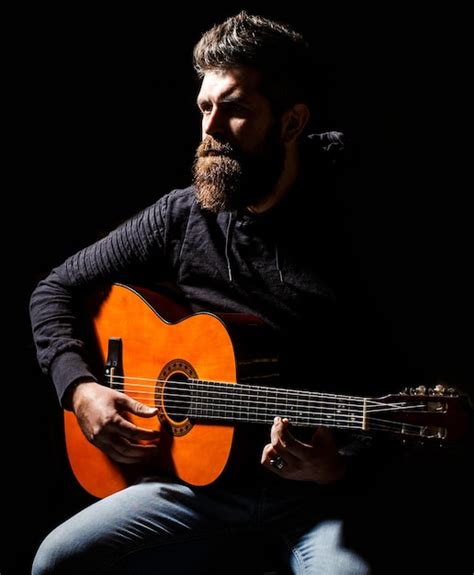 Bearded Man Playing Guitar Holding An Acoustic Guitar In His Hands