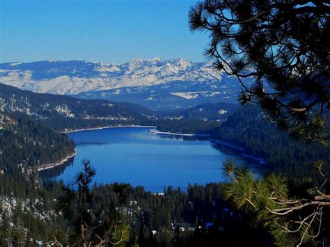 a lake surrounded by snow covered mountains and pine trees