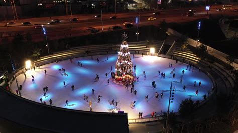 People ice skate around a Christmas tree in a skating rink at night