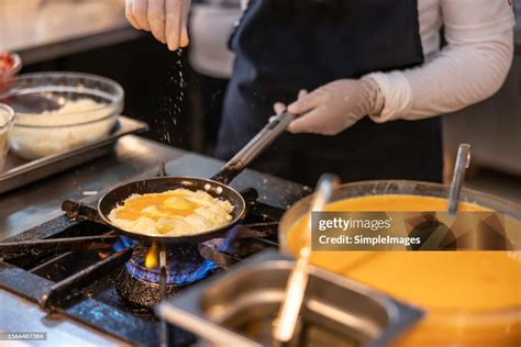 A Chef Prepares An Omelet Or Scrambled Eggs In A Restaurant Kitchen She Seasons The Food With