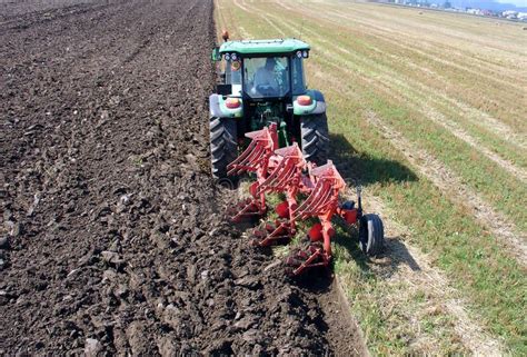 Ploughing. Soil with modern plough and farm tractor on the agriculture ...