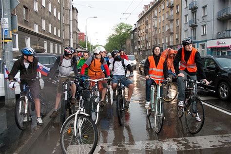 A Group Of Bicyclists Riding Down The Street On A Rainy Day With Orange