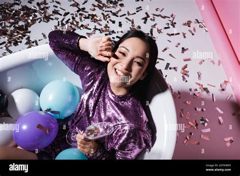 Top View Of Happy Asian Woman Lying In Bathtub With Balloons And