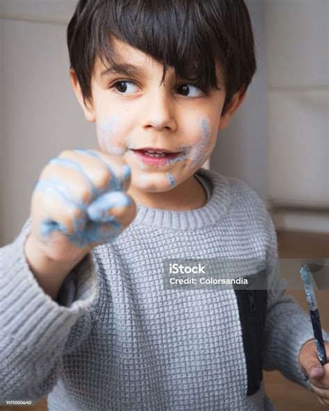 Boy With Face Smeared With Blue Paint Clenching His Fist Stock Photo