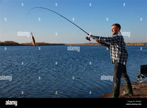 Fisherman Catching Fish With Rod At Riverside Stock Photo Alamy