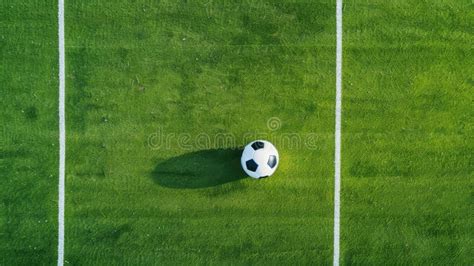 A Soccer Ball Sits On A Green Grass Field With White Lines Marking The