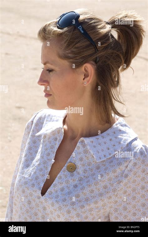 Side View Of A Woman Standing On A Beach With Sunglasses On Her Head