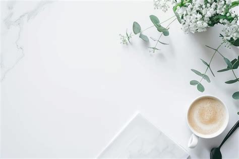 Una taza de café con un fondo blanco con flores y una tableta Foto