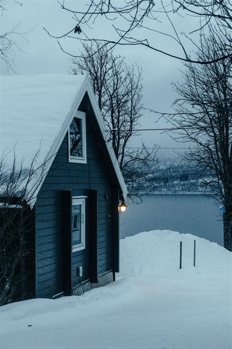 A small cabin in the snow near a lake · Free Stock Photo