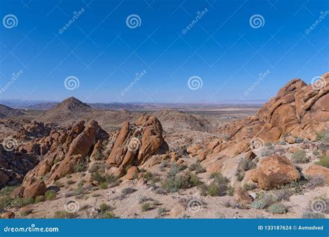 A Desert With Rock Formations Valleys And Distant Mountain Chain On