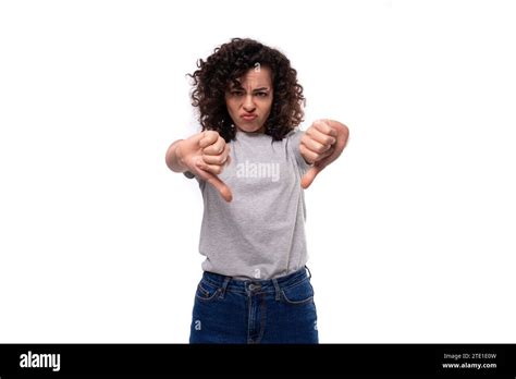 Upset Slender Curly Brunette Promoter Woman With Glasses Is Dressed In A Gray Basic T Shirt On A
