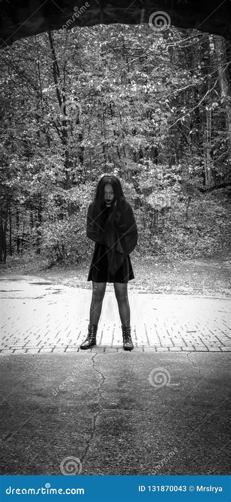 Portrait Of A Girl Dressed In All Black Standing In A Forest Stock