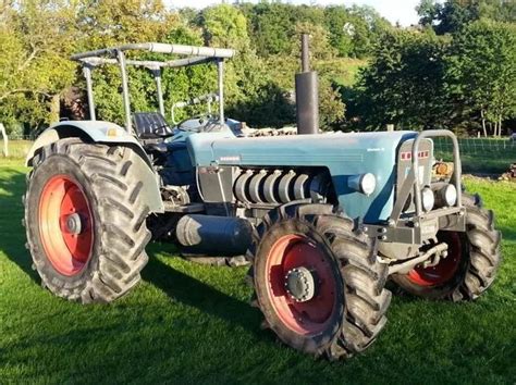 A Blue Tractor Parked On Top Of A Lush Green Field