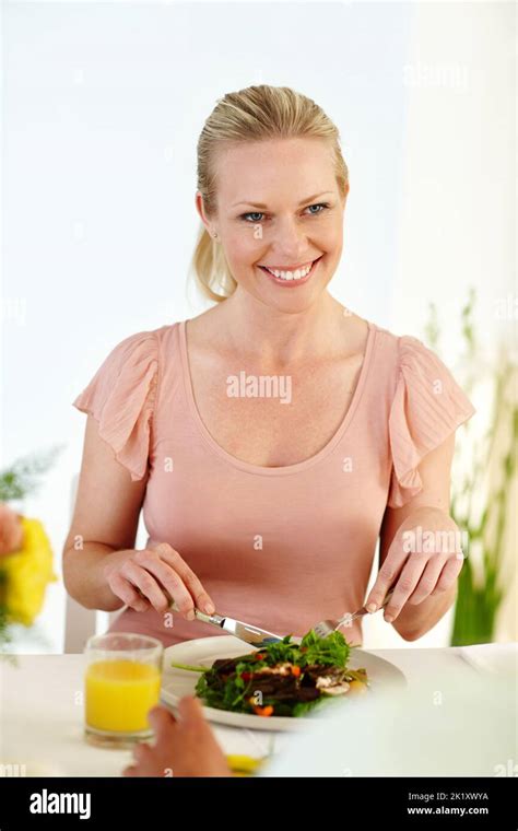 Enjoying A Healthy Lunch A Beautiful Woman Enjoying A Healthy Lunch In Her Dining Room Stock