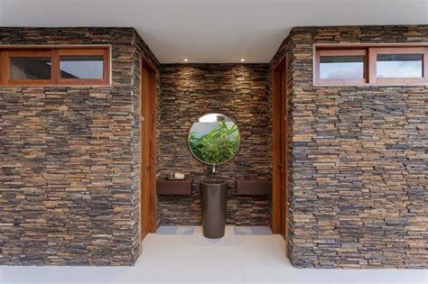 there is a mirror in the middle of this room with stone walls and flooring